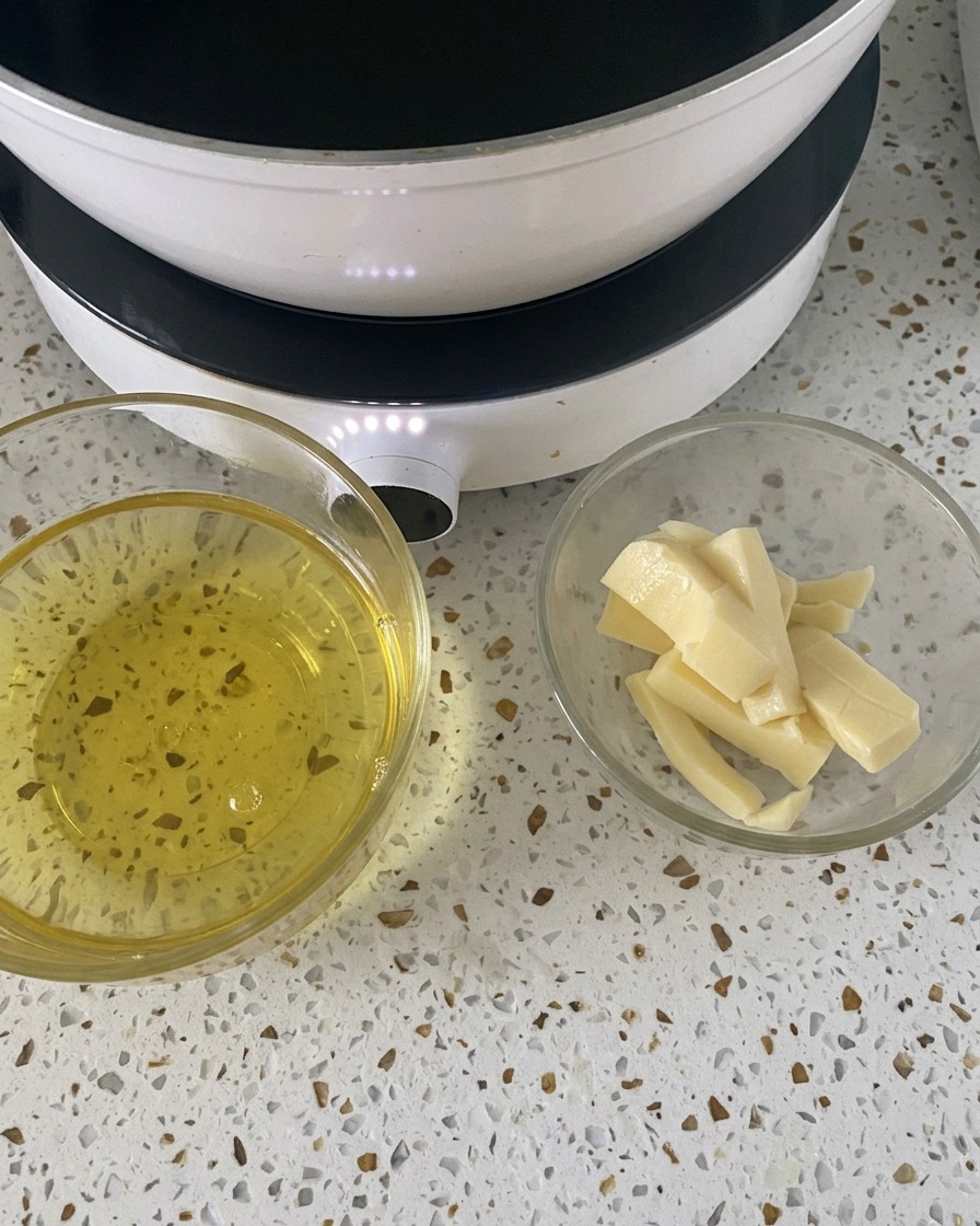 Dos pequeños cuencos de cristal con huevos crudos y rebanadas de mozzarella sobre una encimera blanca junto a un hornillo.