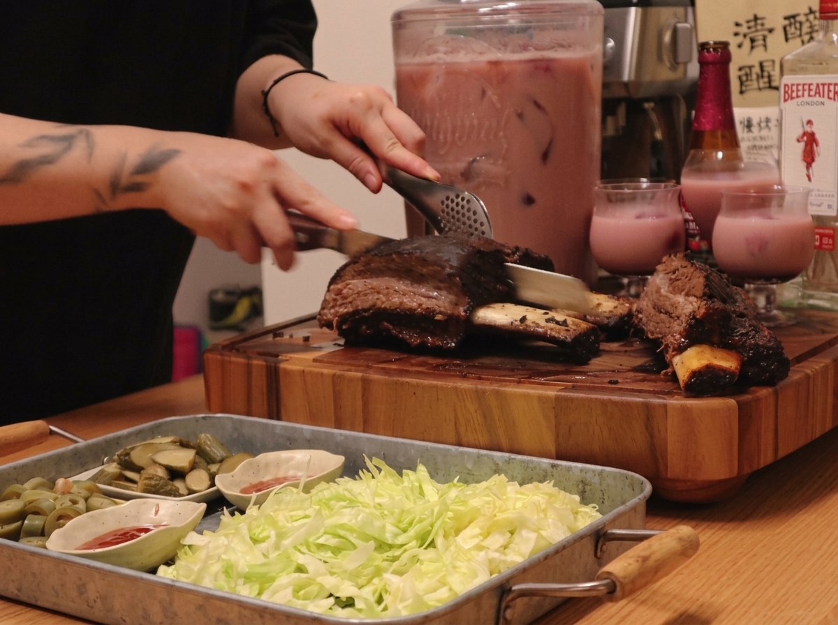 Plato con costillas de res cortadas junto a lechuga, pepinillos y boles con salsa roja.