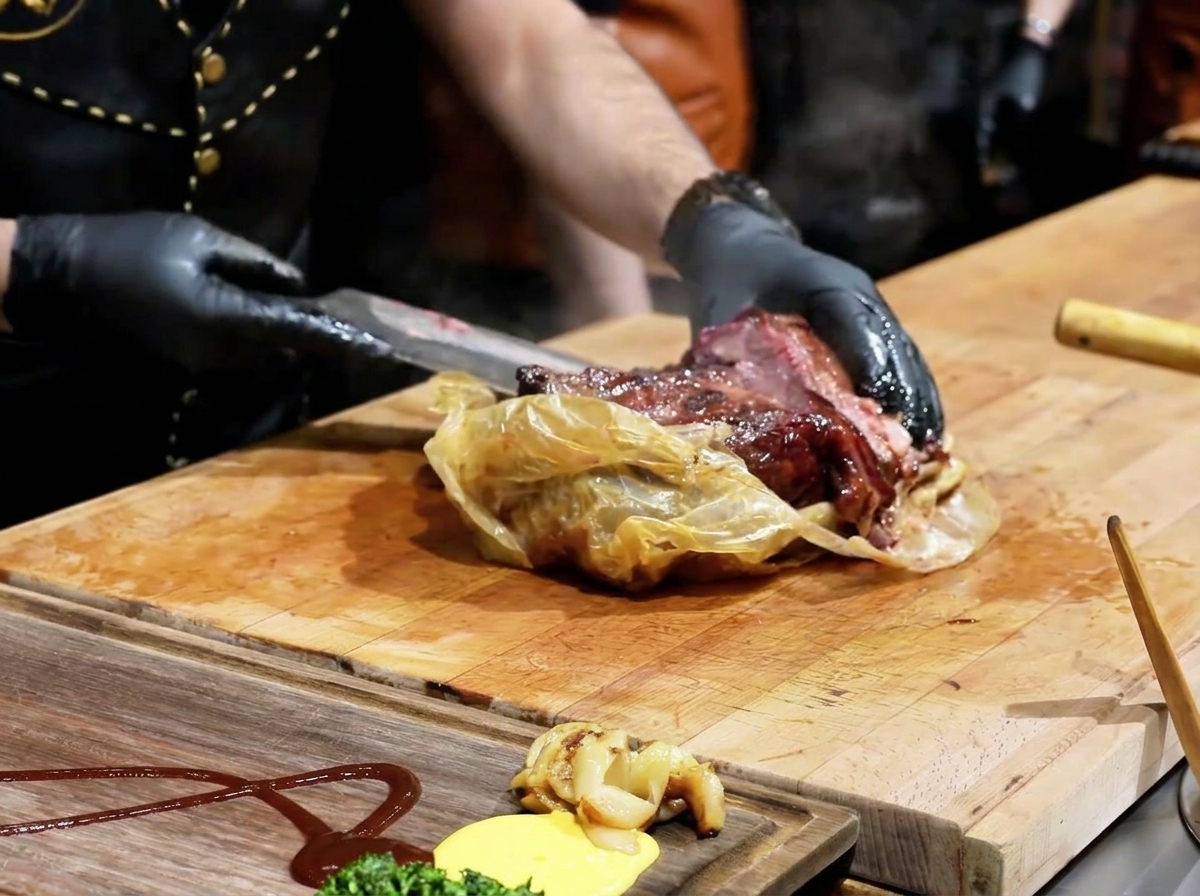 Chef usando un cuchillo para abrir un envoltorio, revelando un brisket oscuro y suculento en una tabla de madera