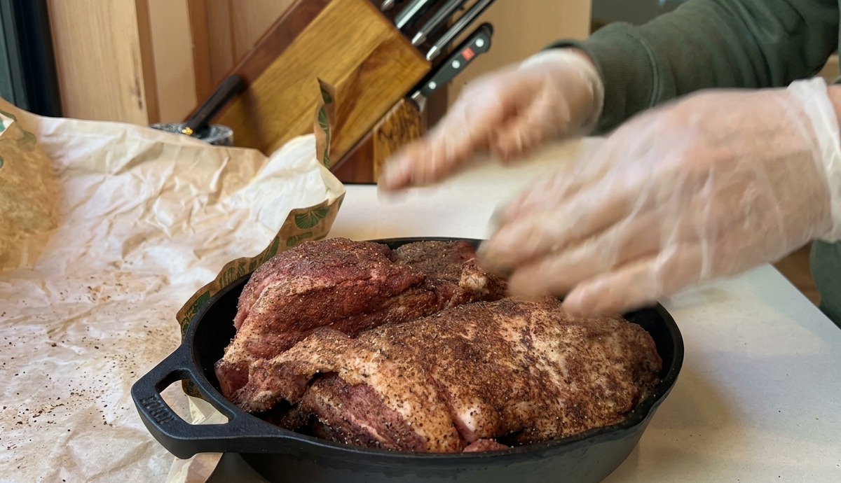 Una paleta de cerdo sazonada en una sartén de hierro, lista para ser asada en un horno precalentado.