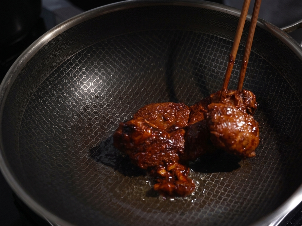 Trozos de cerdo marinado sellándose en un wok caliente, mostrando una costra dorada y apetitosa.