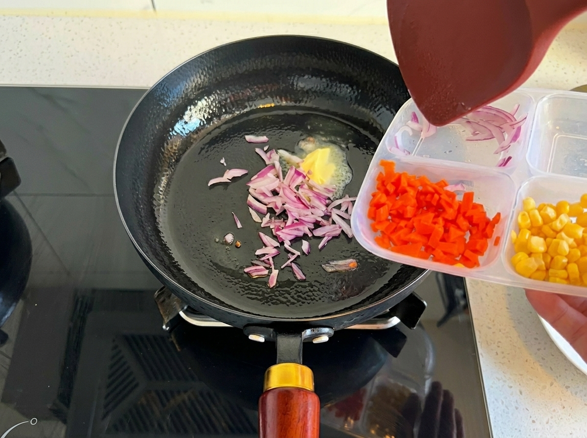 Cebolla morada picada siendo añadida a una sartén con mantequilla derretida.