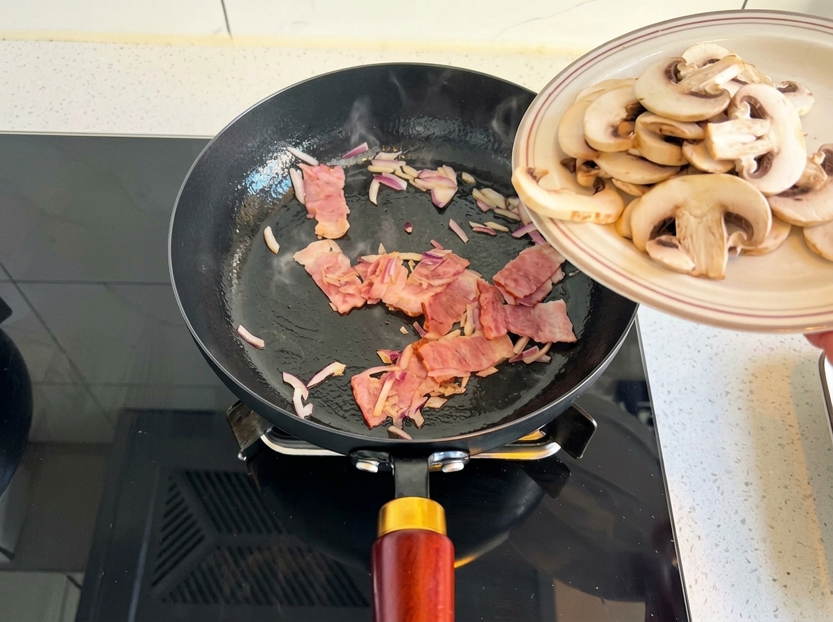Champiñones laminados deslizándose de un plato a una sartén con cebolla y tocino.
