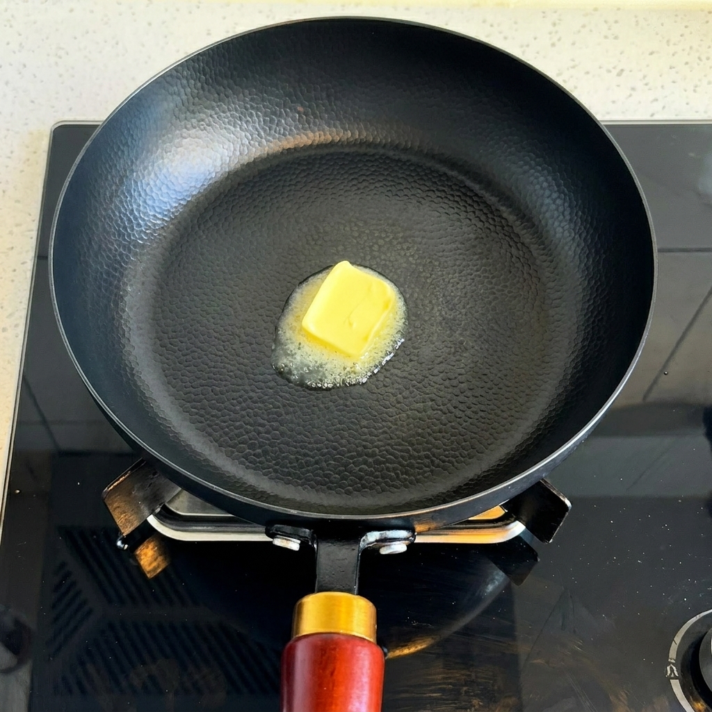 Un trozo de mantequilla derritiéndose en una sartén caliente.