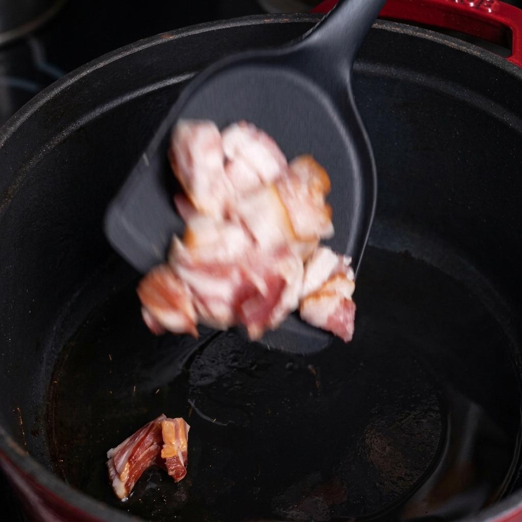 Trozos de bacon picado cayendo a una olla de hierro caliente.