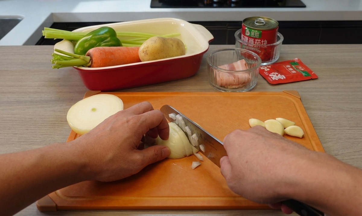 Dos manos sosteniendo un cuchillo de cocina y picando finamente una cebolla blanca en una tabla de cortar naranja, con dientes de ajo cerca.