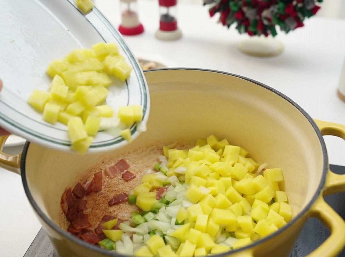 Dados de patata, apio y cebolla pasando de un plato blanco a la olla con el bacon restante.