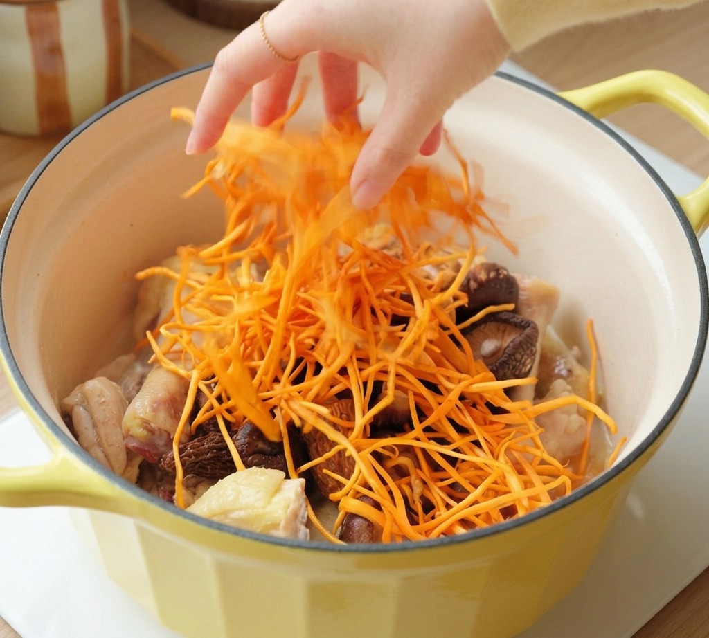 Una mano esparciendo flores de cordyceps de color naranja brillante sobre el pollo y las setas.