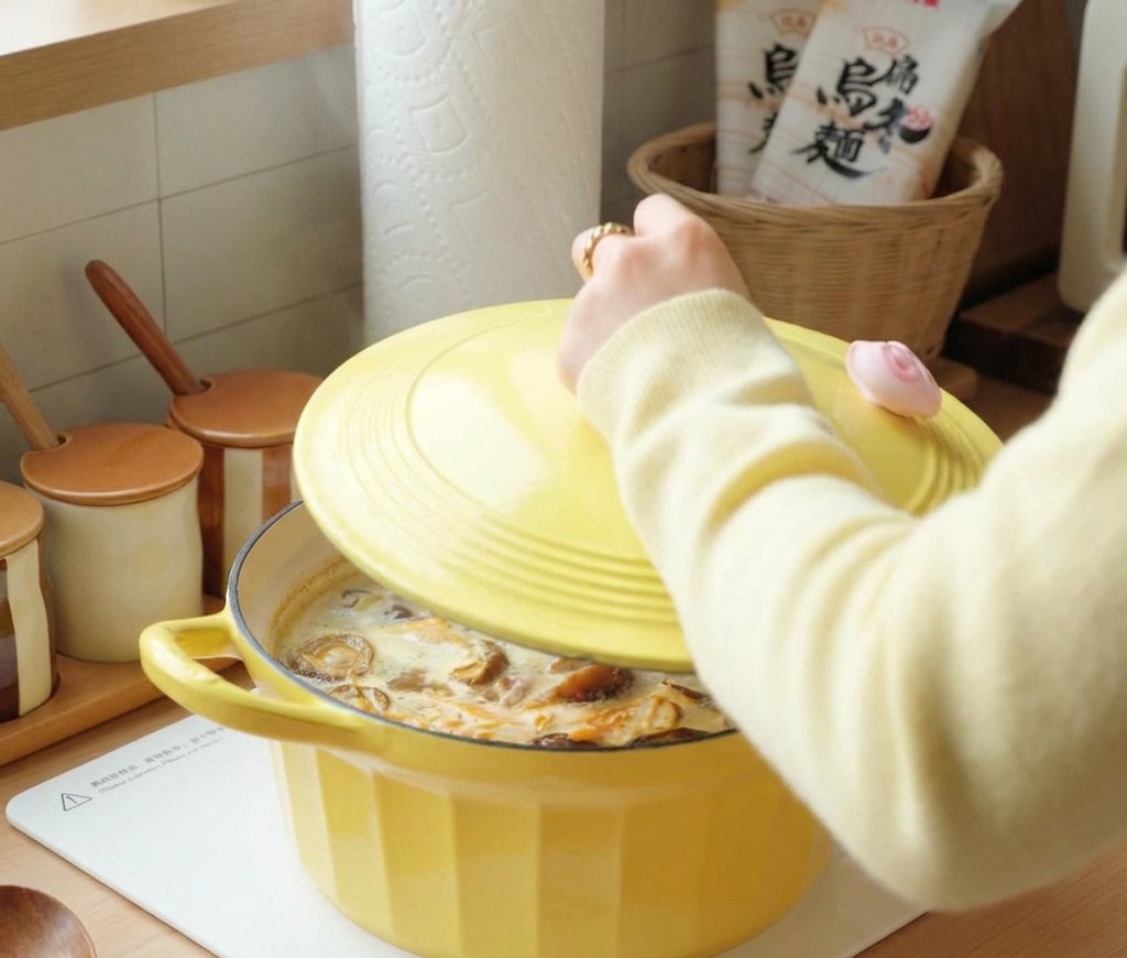 Una persona colocando la tapa amarilla en la olla humeante de sopa de pollo y setas.
