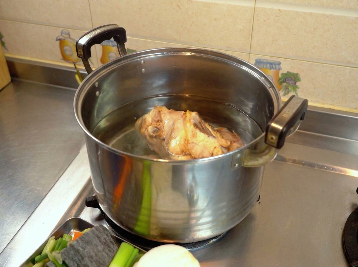 Carcasa de pollo en una olla grande con agua clara sobre la estufa.