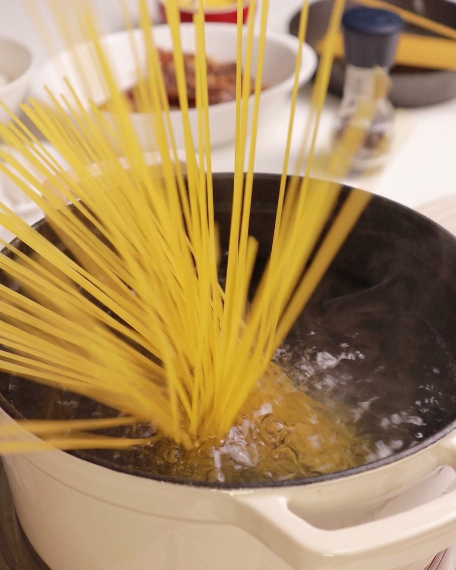 Espaguetis secos introduciéndose en una olla de agua hirviendo.