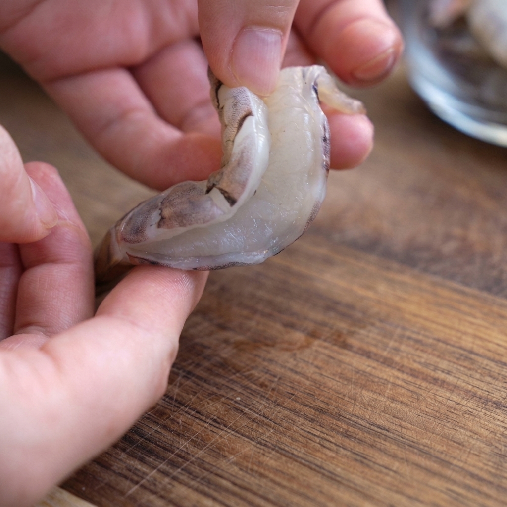 Un langostino crudo y pelado abierto por la espalda para mostrar cómo se desvena.