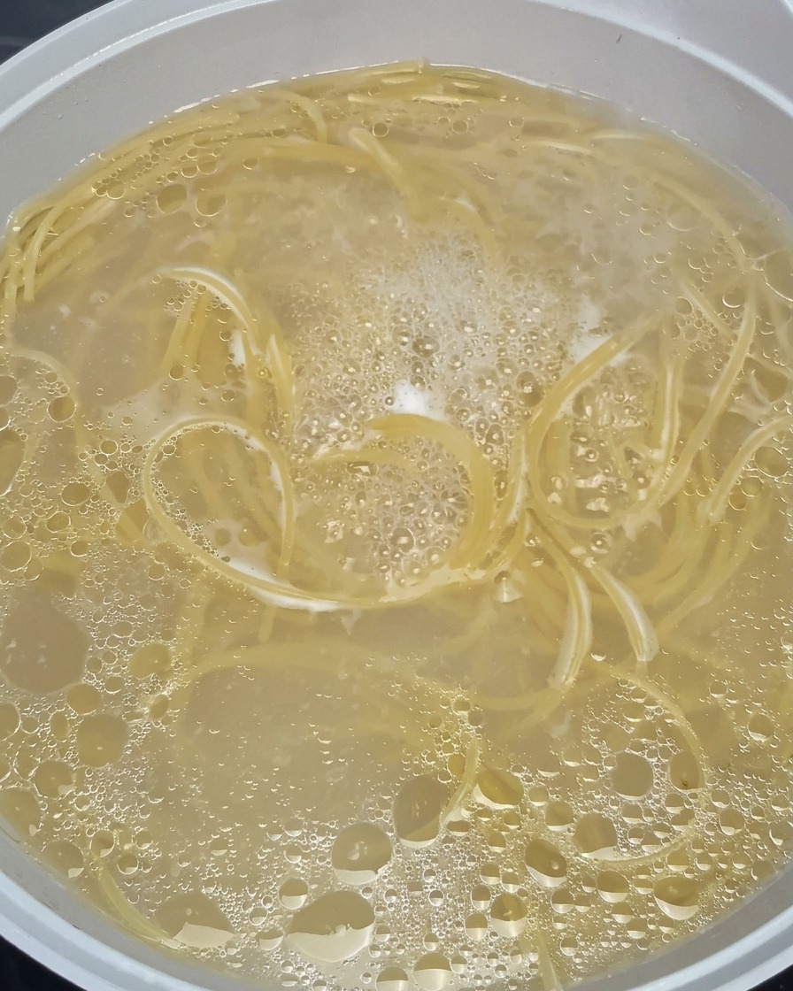 Espaguetis ablandándose en una olla con agua hirviendo a borbotones.