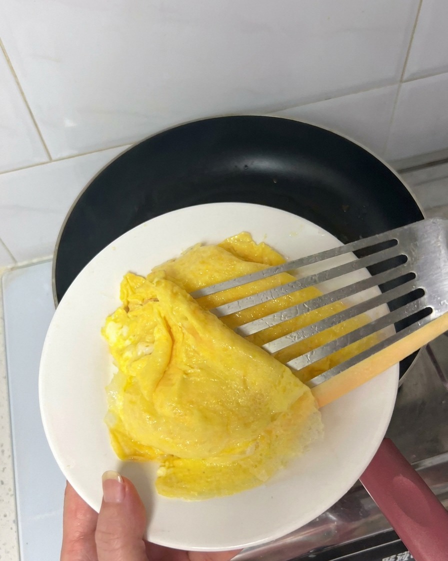Tiras de bacon friéndose y soltando grasa en una sartén caliente.