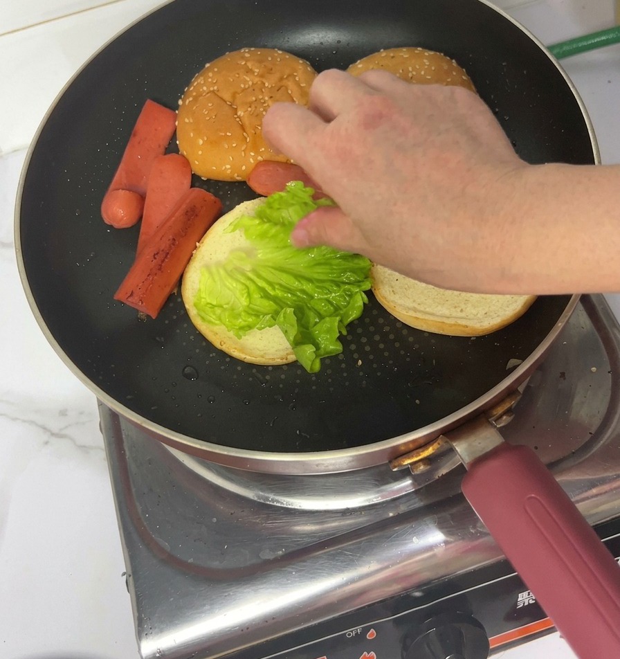 Una mano colocando una hoja de lechuga fresca sobre el pan tostado.