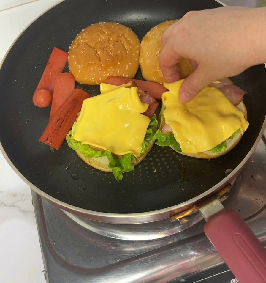 Manos usando pinzas para colocar trozos de jamón cocinado sobre el queso.
