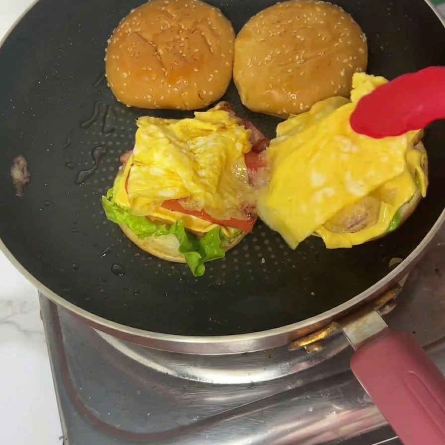 Hamburgesa de desayuno terminada en un plato con la tapa de sésamo en su lugar.