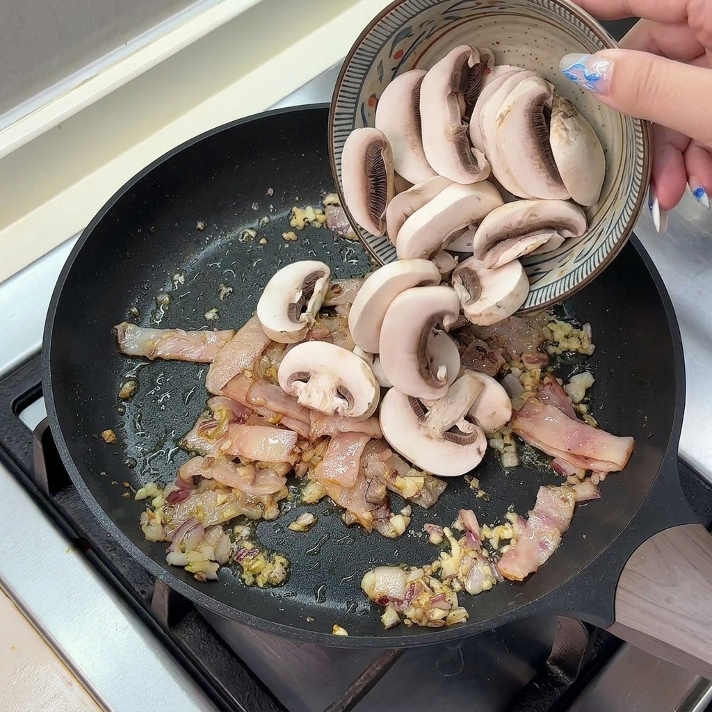 Champiñones frescos laminados cayendo en la sartén con bacon, cebolla y ajo.