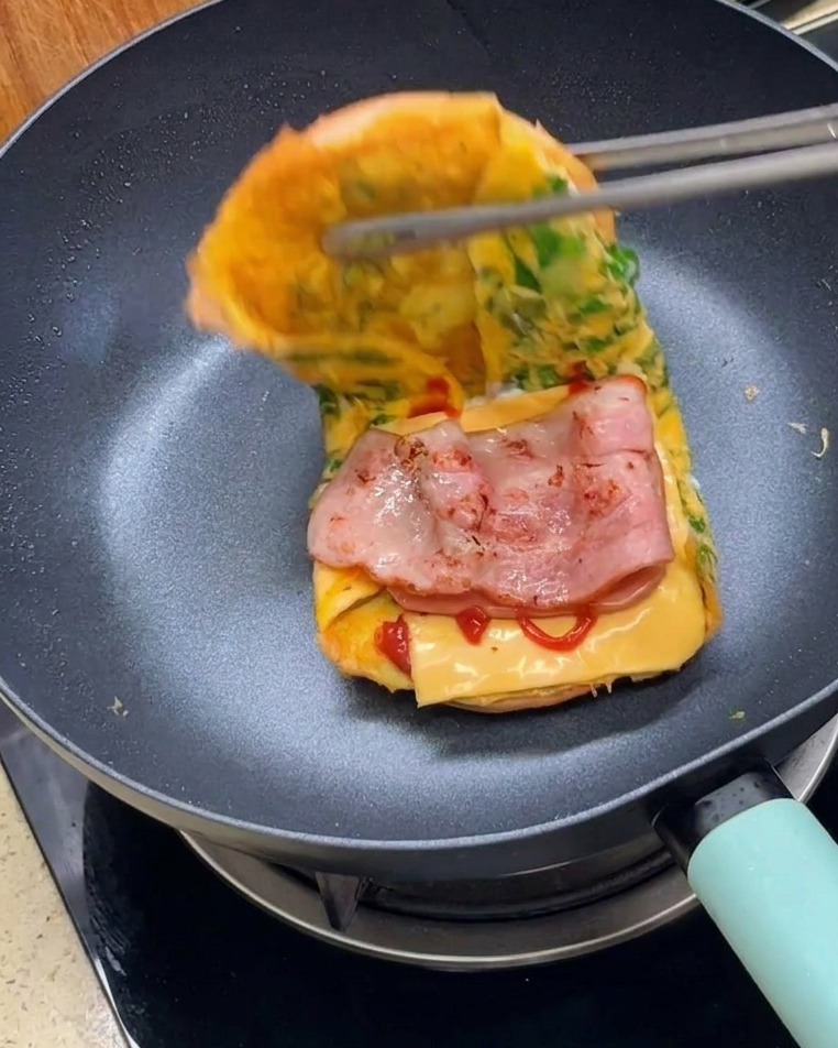 Unas pinzas doblando las dos mitades del pan envuelto en tortilla para cerrar el sándwich.