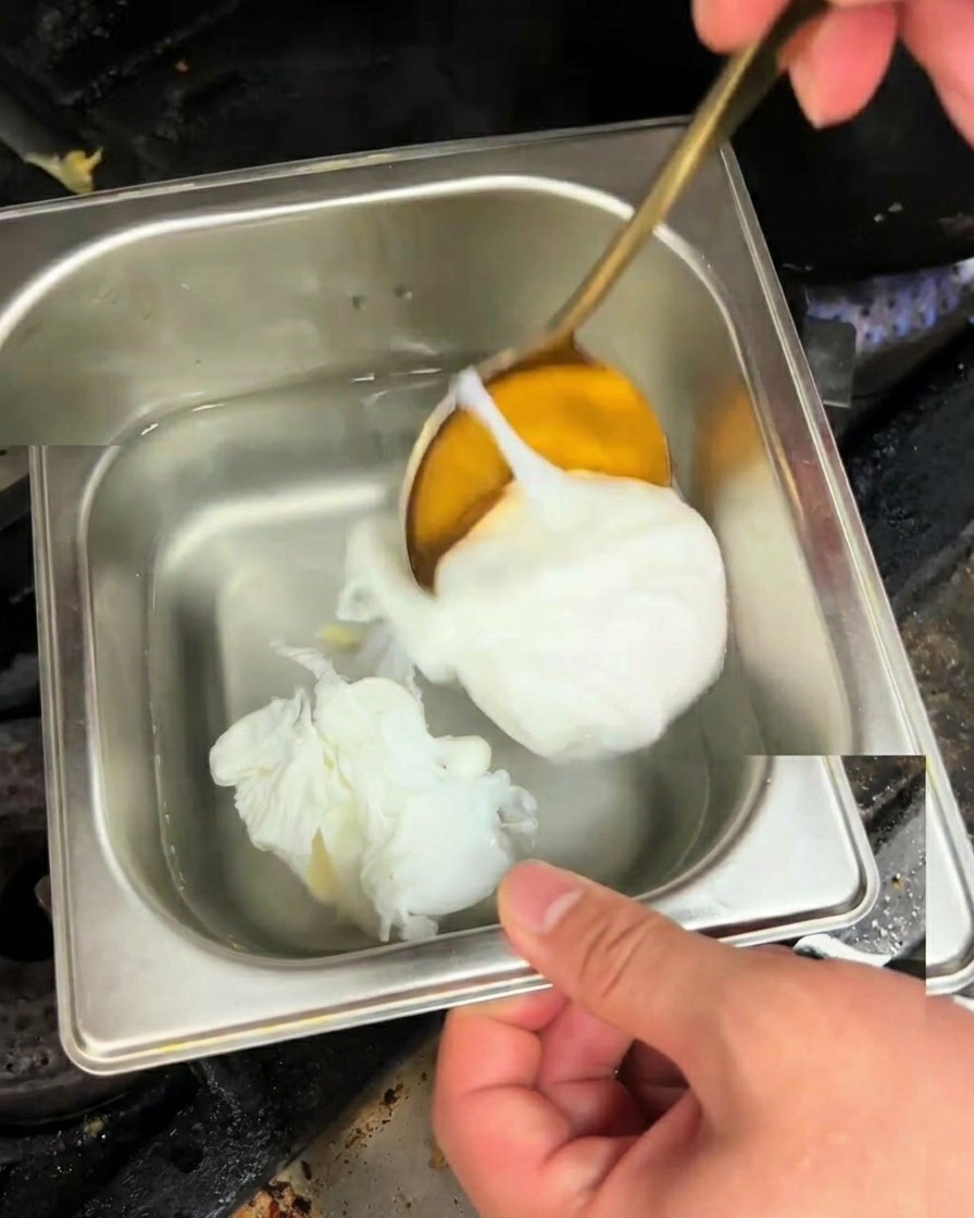 Un huevo poché perfectamente cocinado siendo levantado con una cuchara dorada.