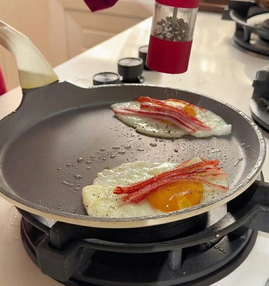 Moliendo sal marina y pimienta negra con un molinillo rojo sobre los huevos y el cangrejo en la sartén.