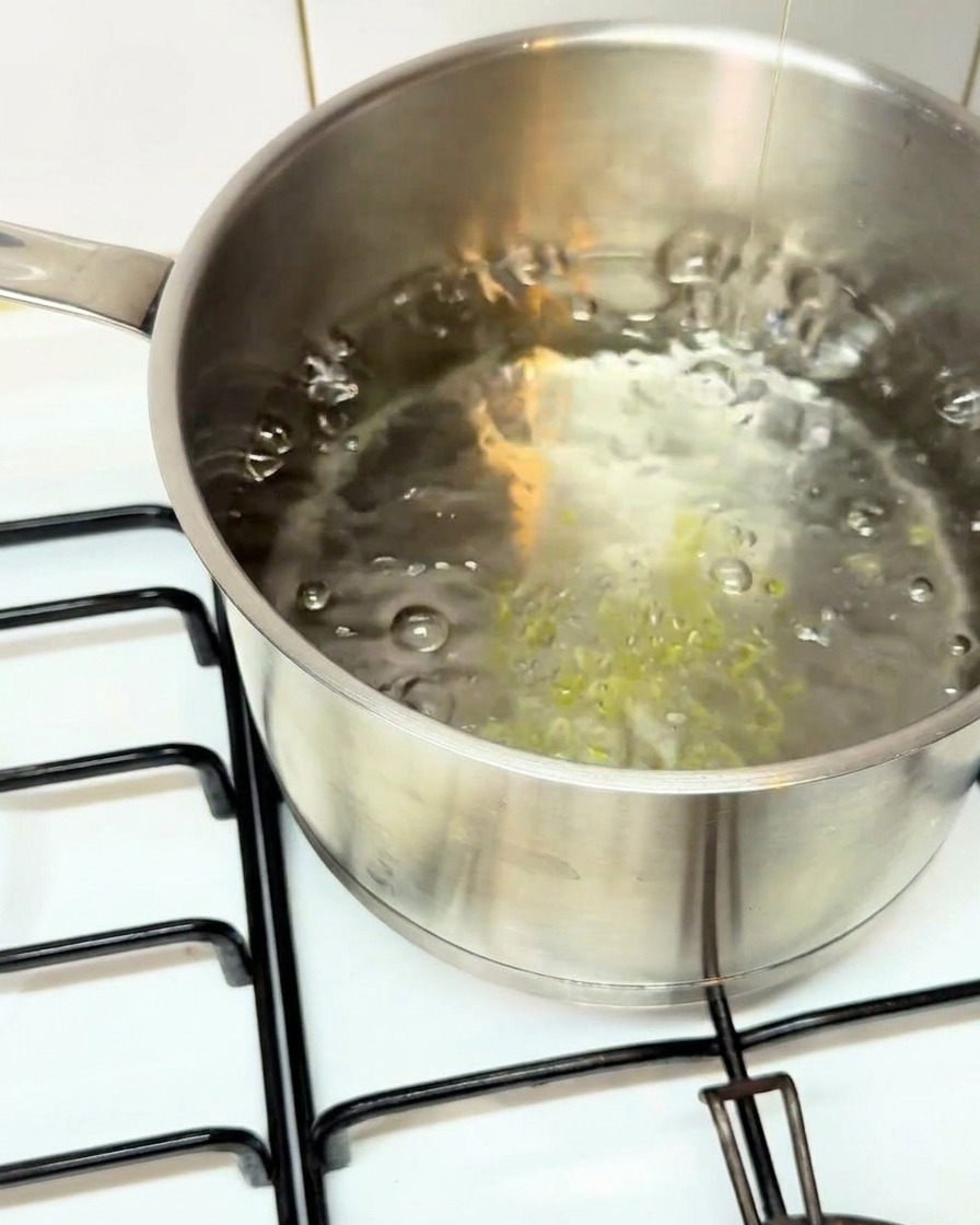 Tubos de pasta paccheri cayendo en una olla de agua hirviendo.
