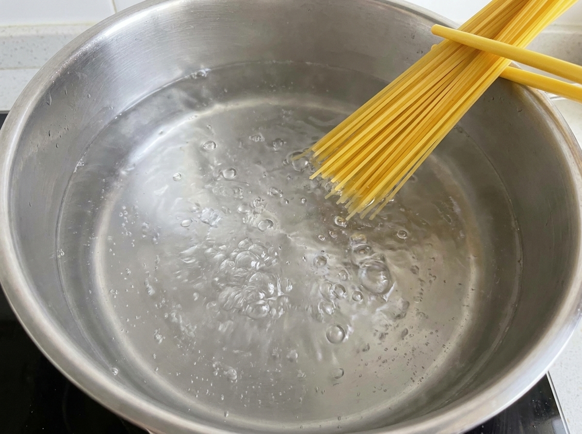 Espaguetis secos sumergiéndose en una olla con agua hirviendo.