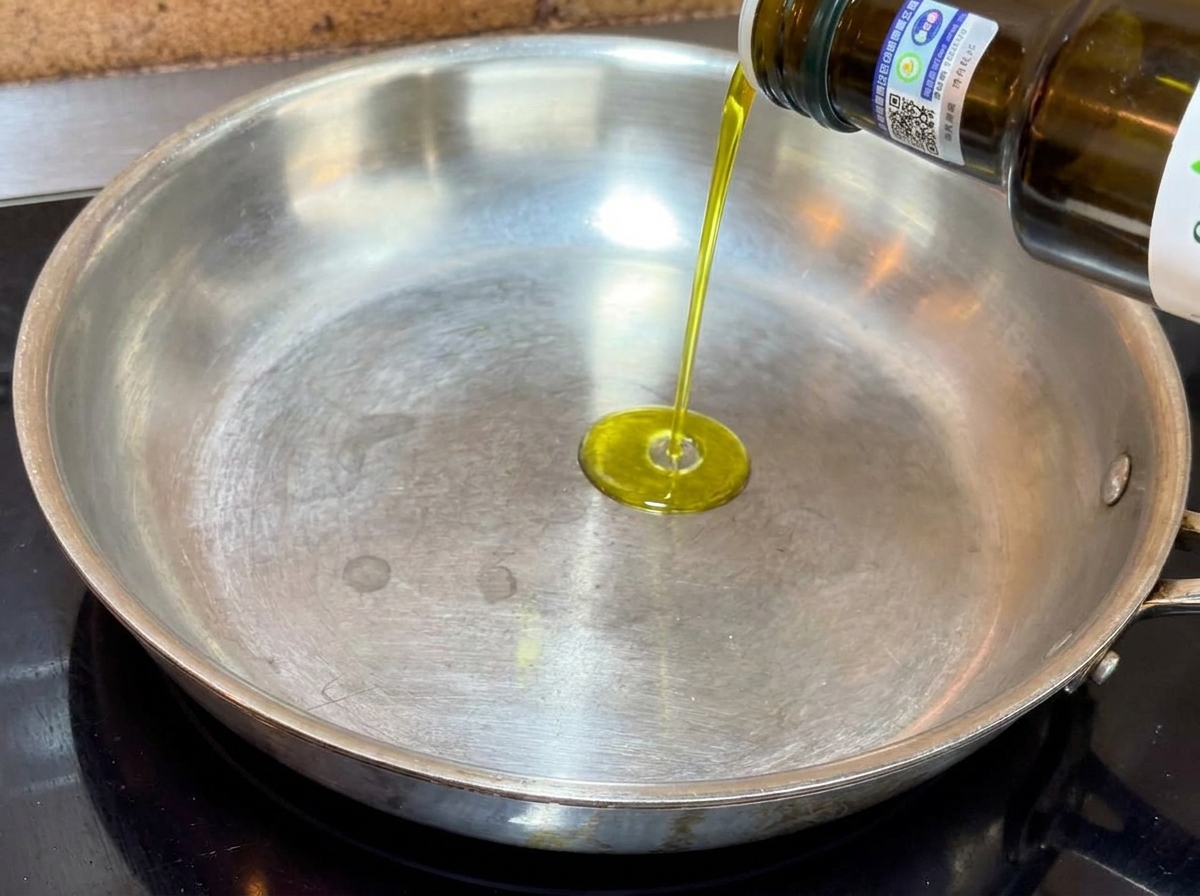 Aceite de oliva virgen extra vertiéndose en una sartén metálica de fondo plano.
