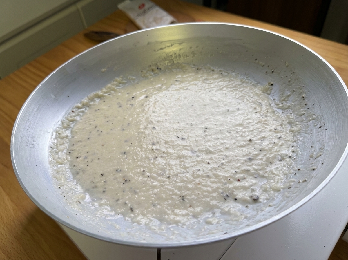 Primer plano de una pasta suave y cremosa hecha de queso Pecorino y pimienta negra en una sartén.