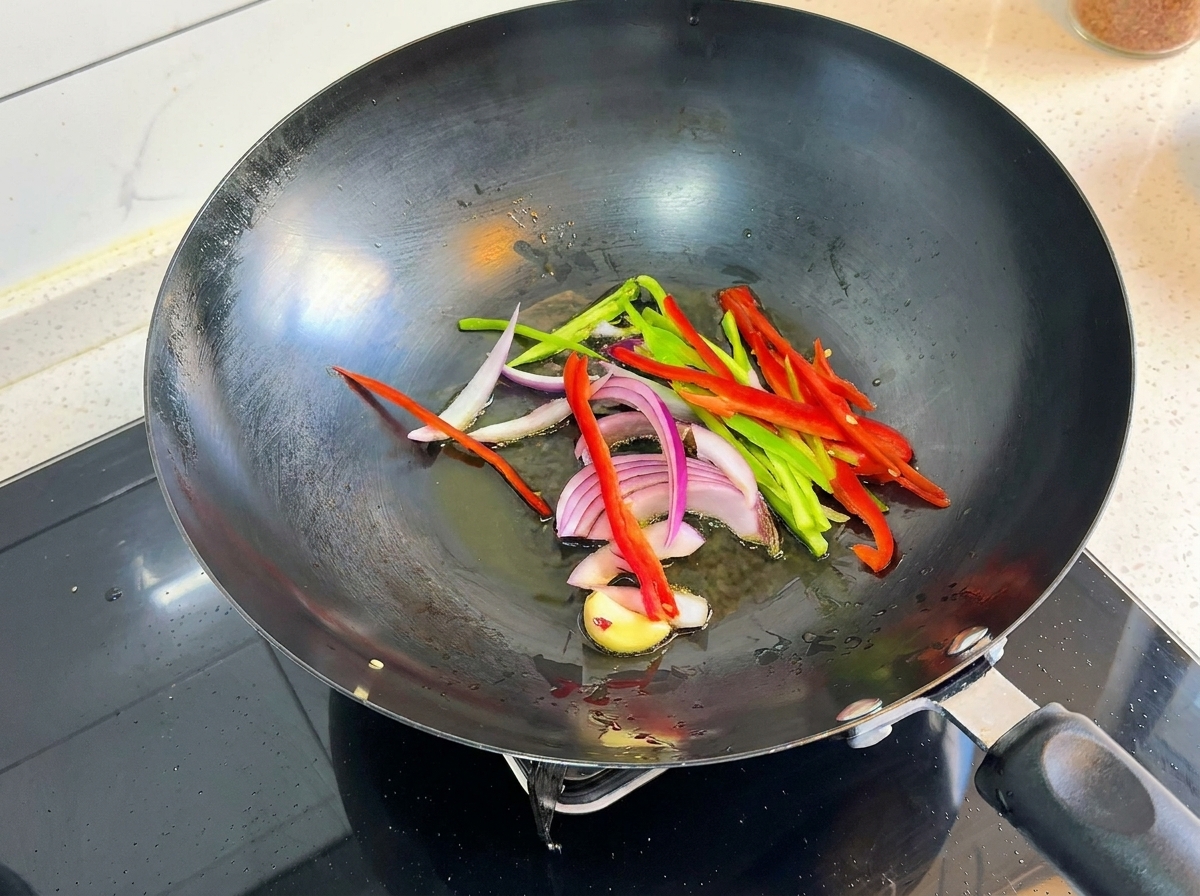 Pimientos cortados, cebolla morada y ajo chisporroteando en un wok caliente.