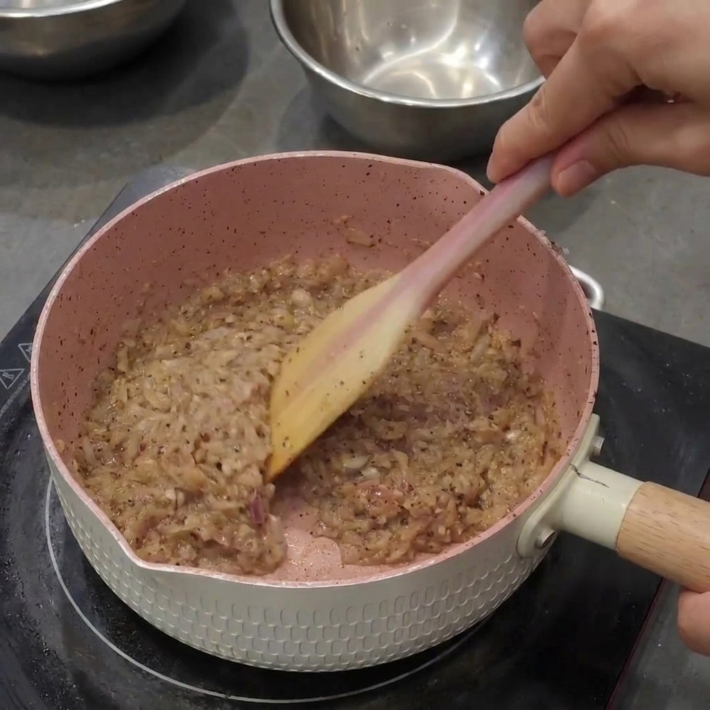 Removiendo la pimienta negra con la cebolla y el ajo sofritos, formando una pasta oscura y espesa.