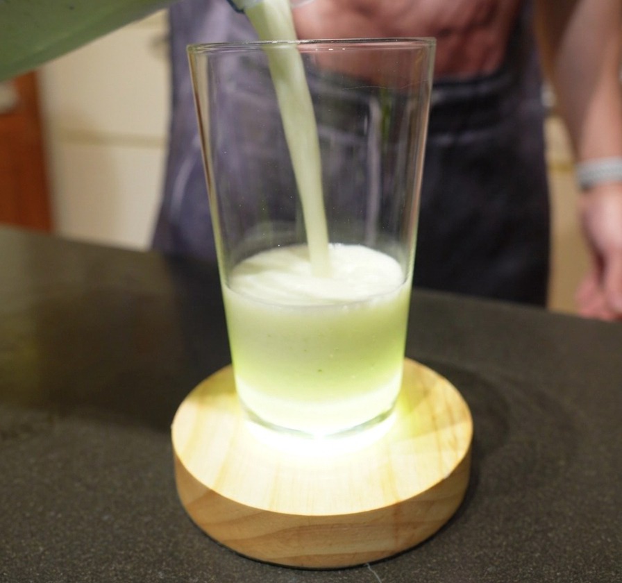Sirviendo una bebida de lima batida, cremosa y de color verde pálido, en un vaso alto.