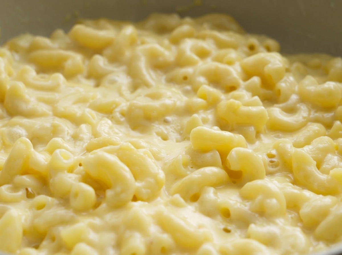 Vista en primer plano de macarrones con queso cremosos en una sartén.