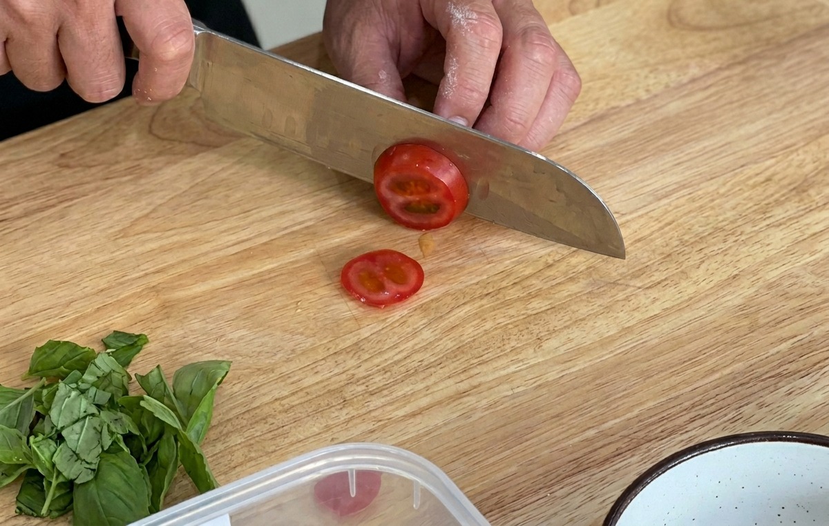 Cortando tomates cherry frescos sobre una tabla de madera.