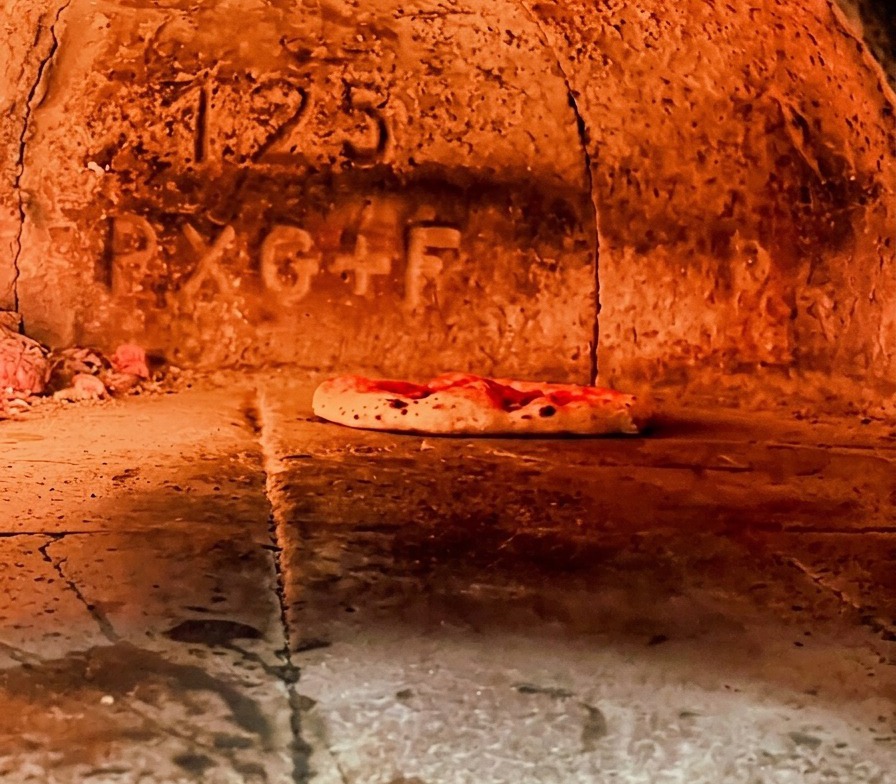 Pizza napolitana horneándose en un horno de leña muy caliente con la masa empezando a hincharse.