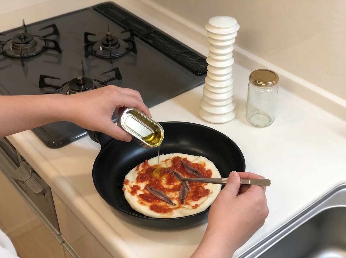 Usando unas pinzas para colocar anchoas enteras en lata sobre la salsa de pizza mientras se vierte un chorrito de aceite de la lata de anchoas.