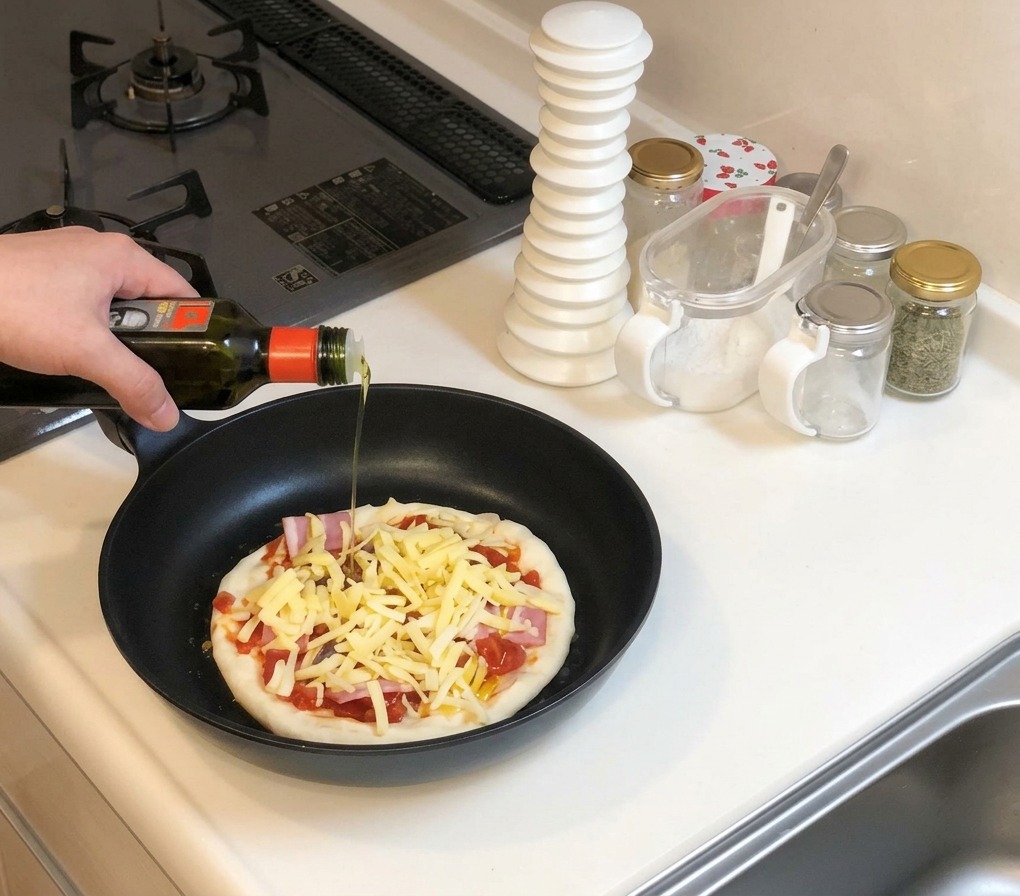 Una mano sosteniendo una botella de aceite de oliva, rociándolo sobre la pizza cruda cubierta de queso en una sartén negra.