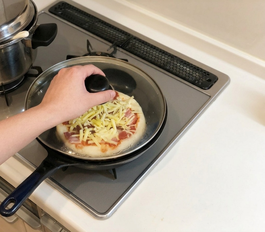 Una mano colocando una tapa de vidrio sobre una sartén que contiene la pizza en una estufa de gas.