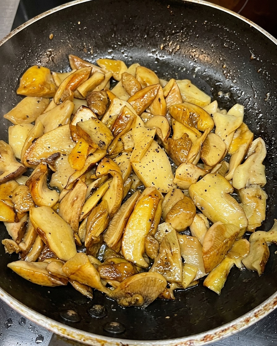 Champiñones laminados dorándose en una sartén caliente.