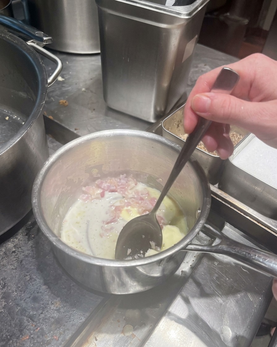 Chalotas picadas cocinándose en mantequilla derretida en un cazo.