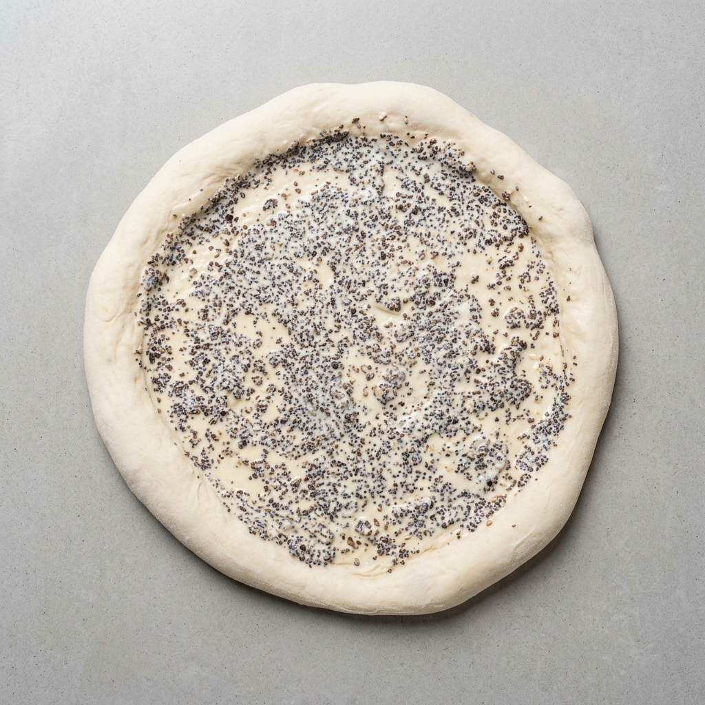 Masa de pizza cubierta de forma uniforme con una capa de salsa de trufa negra.