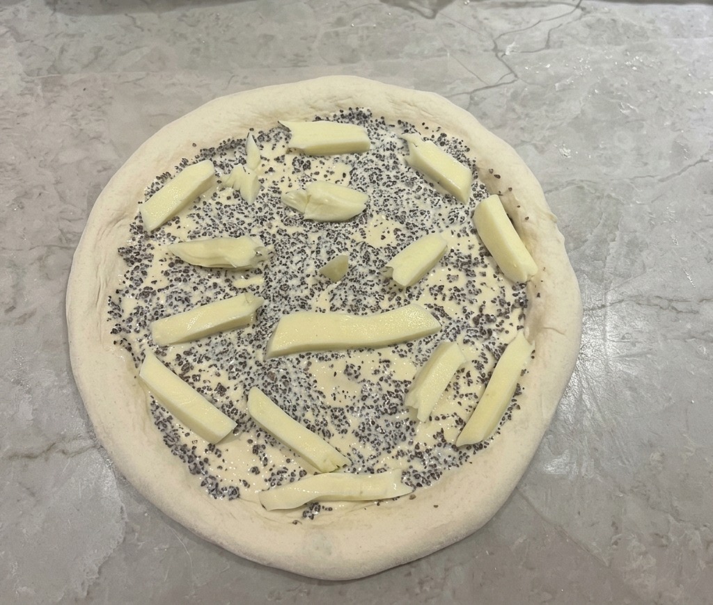 Base de pizza con salsa de trufa y trozos de queso mozzarella distribuidos por encima.