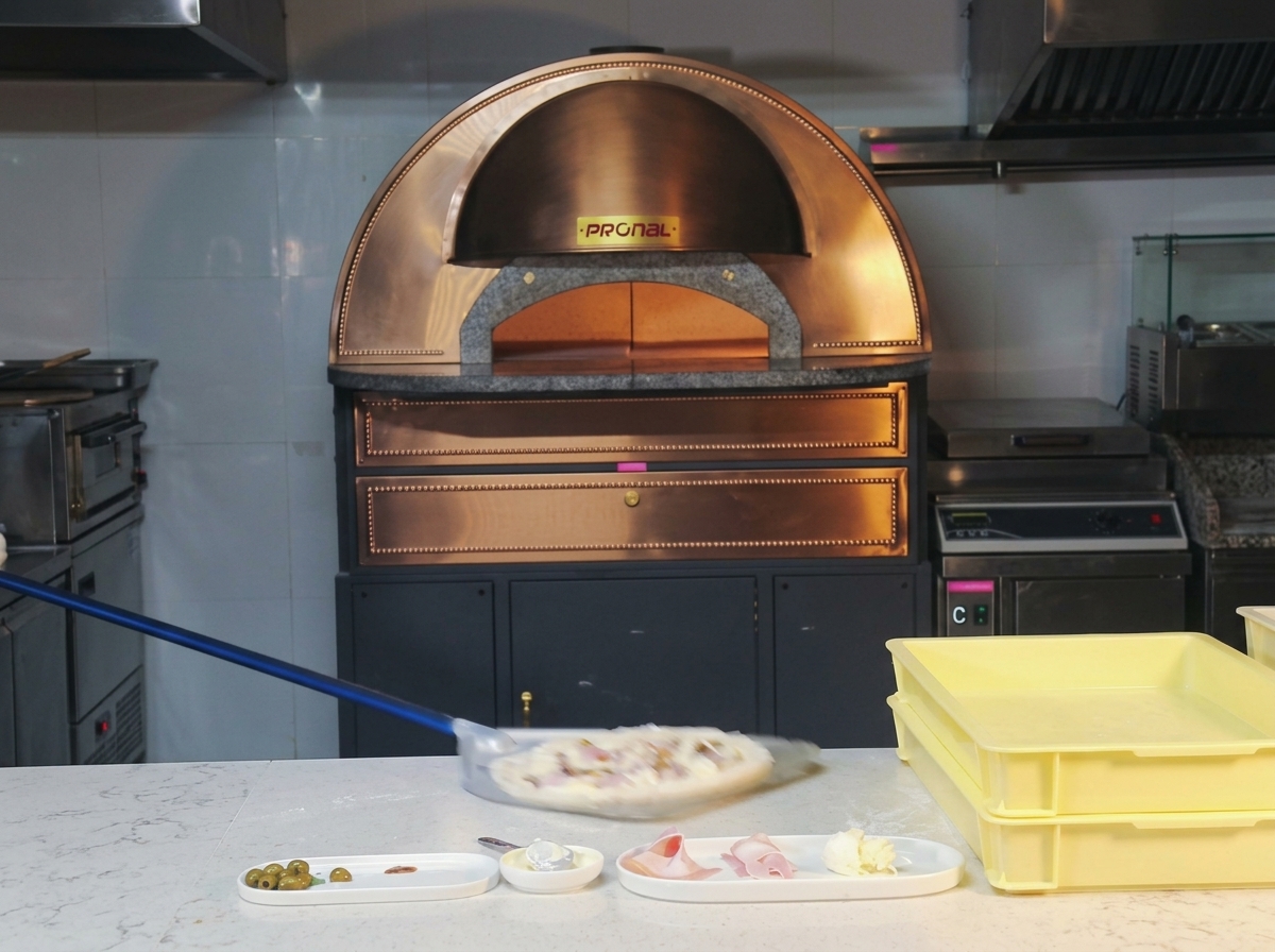 Una pizza de jamón y champiñones entrando en un horno de cúpula caliente.
