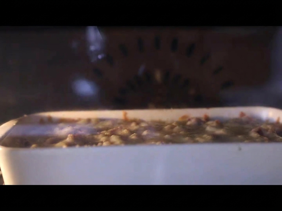 Primer plano de la fuente dentro del horno caliente, con el queso burbujeando y fundiéndose.
