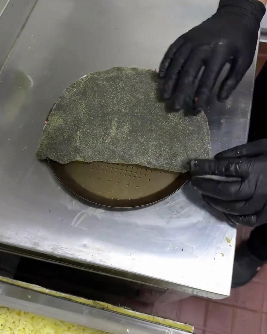Manos doblando la masa negra para formar un calzone en forma de media luna.