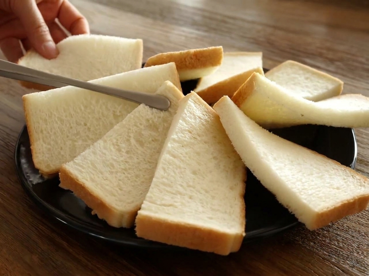 Mitades de pan de molde dispuestas en un círculo superpuesto sobre un plato de horno negro.