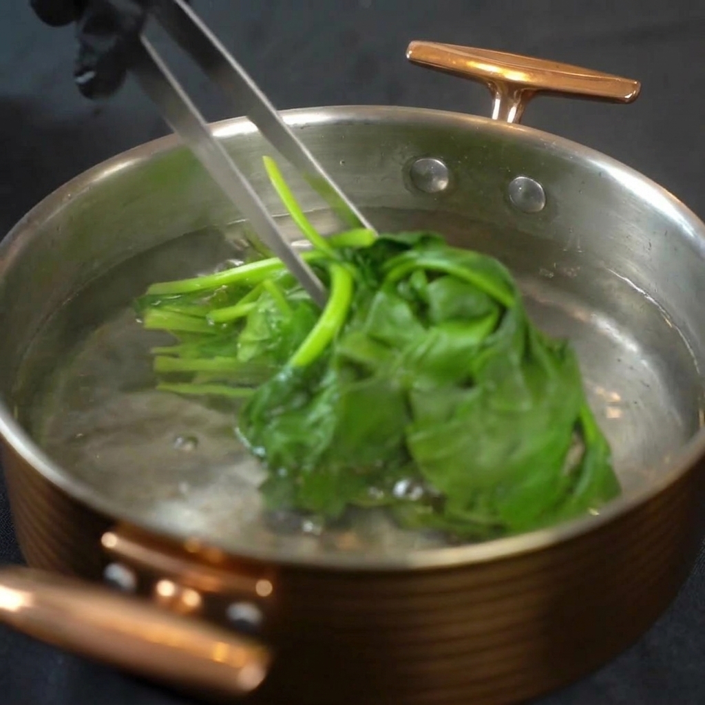 Pinzas de metal sacando las espinacas de la olla con agua hirviendo.