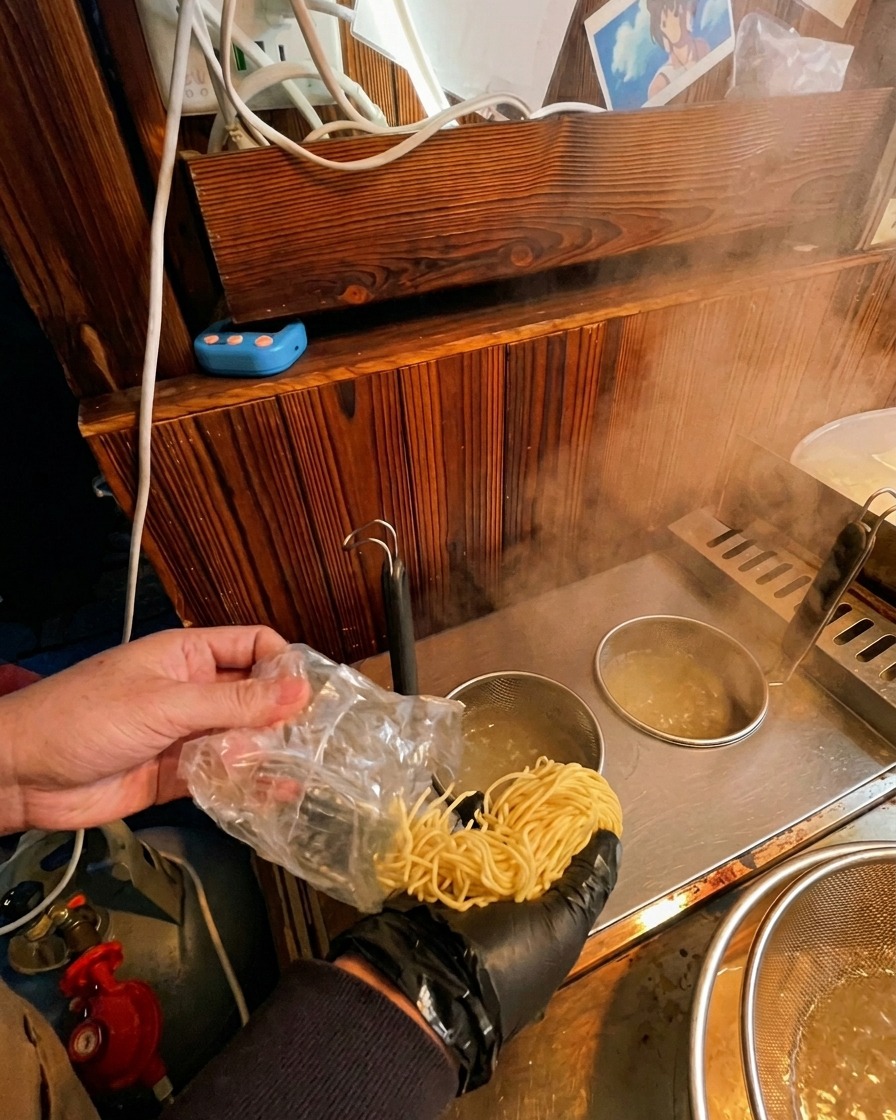 Vaciando fideos ramen frescos desde su envoltorio a una cesta de cocción sumergida en agua hirviendo.