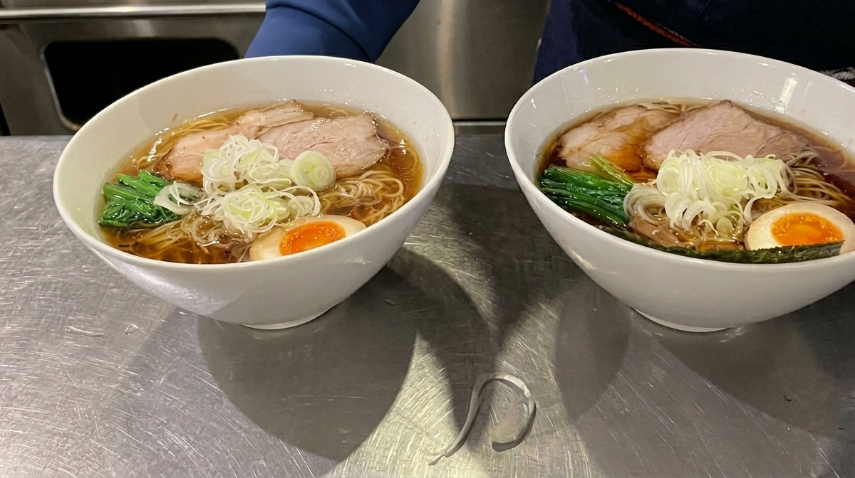 Una hoja cuadrada de alga nori colocada en el borde de un cuenco de ramen humeante como guarnición final.