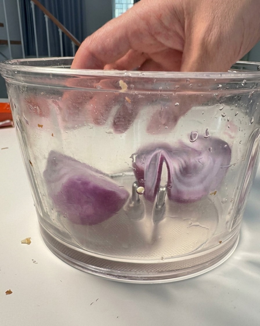 Trozos de cebolla morada dentro de un procesador listos para ser triturados.